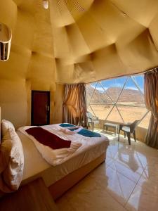 a bed in a room with a large window at Solara Rum Camp in Wadi Rum