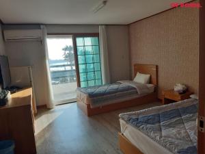 a hotel room with two beds and a window at Jeju Island Love in Jeju