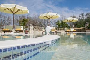 a swimming pool with two umbrellas and chairs and a swimming pool at Epavlis Nadine Corfu in Corfu
