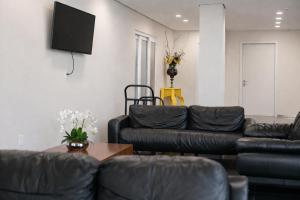 a living room with black leather furniture and a flat screen tv at DE STEFANI HOTEL in Portão