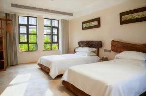 a bedroom with two beds and two windows at Wuzhen FortuneCourt Hotel in Jiaxing