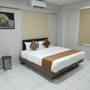 a bedroom with a large bed in a white room at Lexora Hotel in Chharodi