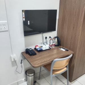 a desk with a phone and a television on a wall at Lexora Hotel in Chharodi