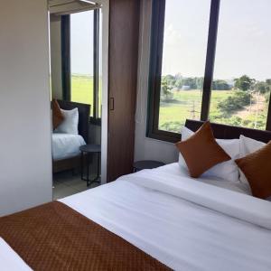 a bedroom with a large white bed with a large window at Lexora Hotel in Chharodi