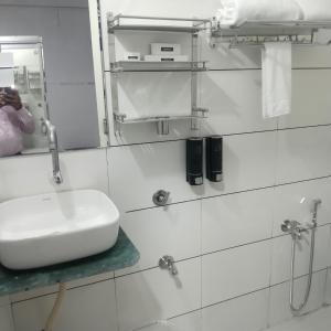 a white bathroom with a sink and a mirror at Lexora Hotel in Chharodi