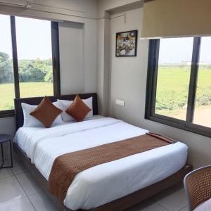 a bedroom with a large bed with large windows at Lexora Hotel in Chharodi