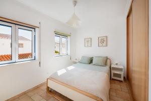 a white bedroom with a bed and a window at Casa de Baixo in Odeceixe