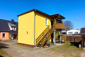 a yellow house with a staircase on the side of it at Ferienwohnung Sonnenblick in Loddin