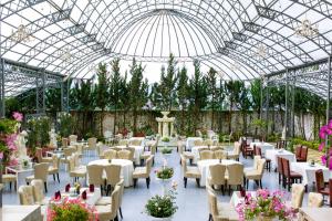 a greenhouse with white tables and chairs and flowers at Mallorie Hotel Dalat in Xuan An