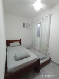 a bed in a white room with a window at Casa Lego Paraty in Paraty