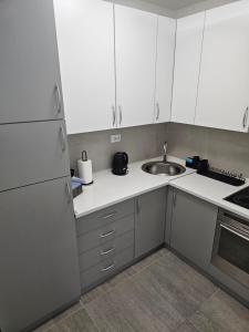 a small kitchen with white cabinets and a sink at Apartman Petrovic-5 min by walk to Center,Doboj City Park in Doboj +11 photos