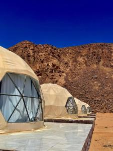 two domes in the desert with a mountain in the background at Solara Rum Camp in Wadi Rum