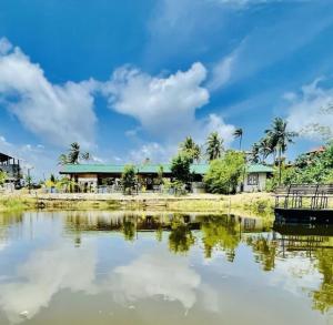 a body of water with a building and palm trees at The Lark Resort ,induruwa in Induruwa