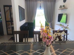 a dining room table with a vase of flowers on it at D'sawah Guest House in Kota Bharu
