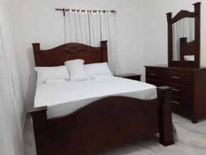a bedroom with a wooden bed with a mirror and a dresser at Villas Reynoso, Near La Playita Beach in Las Galeras Samaná in Las Galeras