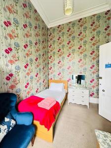 ein kleines Schlafzimmer mit einem Bett und einem Stuhl in der Unterkunft Eliza House in Edinburgh