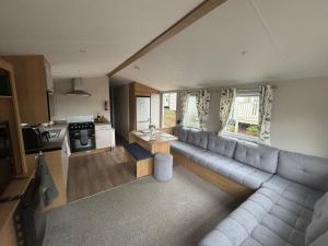 a living room with a long couch and a table at Stylish large static caravan gold rated 3BR Slp 8 Thorness Bay in Porchfield