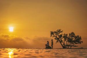 a couple standing on a beach at sunset at Tilar Siro Andamans - A CGH Earth Experience in Havelock Island
