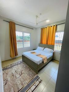 a bedroom with a large bed with orange curtains at SeyniKe 2BR Apartment - Nyali - AC, WiFi - Parking in Mombasa