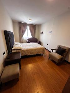 a bedroom with a bed and a couch and a chair at Departamento exclusivo! in Cochabamba