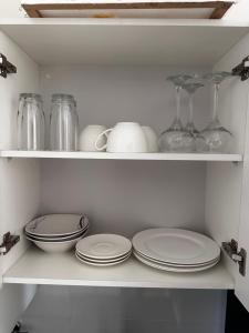 a white shelf with plates and glass dishes on it at Departamento exclusivo! in Cochabamba