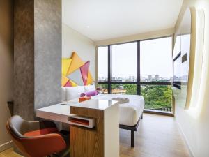 a hotel room with a bed and a desk and a window at Ibis Styles Singapore On Macpherson in Singapore