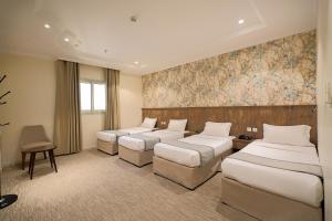 a hotel room with four beds and a wall mural at فندق الخلفاء الماسى الفندقيه in Mecca +29 photos