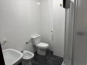 a white bathroom with a toilet and a sink at Razal in Miño
