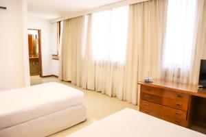 a bedroom with two beds and a dresser with a television at Nobile Hotel Premier Hill in Asunción