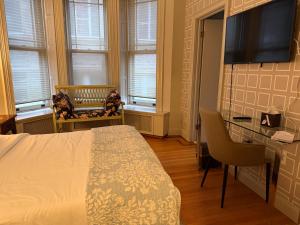 a bedroom with a bed and a desk and windows at Washington Park Inn in Albany