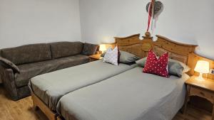 a bedroom with two beds and a couch at Appartamenti Croz del Re 2 in Andalo