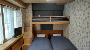 a bedroom with two bunk beds and a television at Oyado Kien Ryogoku in Tokyo