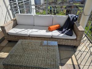 a wicker couch on a balcony with an orange pillow at Coraline -Koblach, 6-10 P, 3 Schlafzimmer, Küche, riesige Terrasse, Parkplatz, WiFi, Stellplatz Ski in Koblach