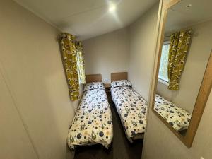 two beds in a small room with a mirror at Stylish large static caravan gold rated 3BR Slp 8 Thorness Bay in Porchfield +12 photos