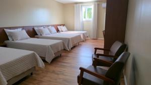 a room with three beds and a couch at Pousada Trapiche in Pelotas
