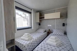 two twin beds in a small room with a window at Mobilhome La Pause Océane - La Plage in Mimizan-Plage +13 photos