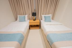 two twin beds in a room with a night stand at Luxury & Modern Brand New Family Apartments in Medina +23 photos