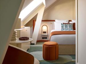 a bedroom with a large bed with an orange stool at l'Echiquier Opéra Hotel Paris - MGallery Collection in Paris +210 photos