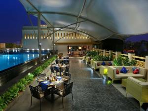 a restaurant with tables and chairs next to a pool at Grand Mercure Mysore - An Accor Brand in Mysore