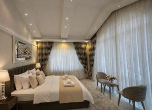 a bedroom with a large bed and two chairs at Villa Nuri Konaklama in Çiftlik