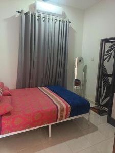 a bedroom with a bed with a curtain and a mirror at D'sawah Guest House in Kota Bharu