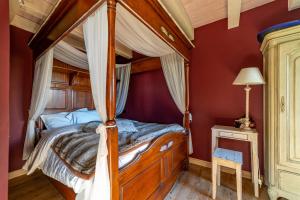 a bedroom with a canopy bed in a red room at Le B Cottage & SPA Privé in Riquewihr +19 photos
