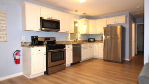 a kitchen with white cabinets and a stainless steel refrigerator at Relaxing Beginnings in Cape May Point
