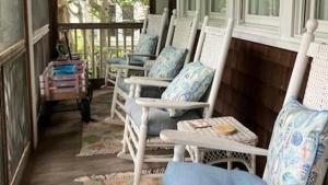 a row of rocking chairs sitting on a porch at Cutest Cottage On Central in Cape May Point