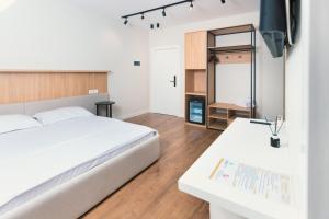 a bedroom with a large white bed and a desk at Hotel Relax City Center in Tirana