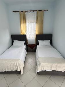 two beds in a room with a window at Antoni Guest House & Café in Lekaj