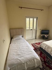 a bedroom with two beds and a sliding glass door at Antoni Guest House & Café in Lekaj