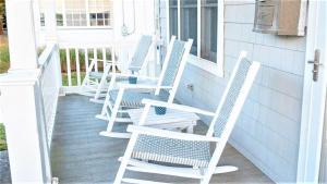 a row of white chairs sitting on a porch at Gray Cottage On Windsor in Cape May