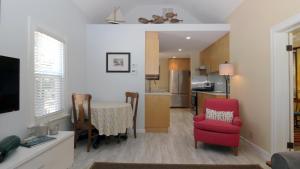 a living room and kitchen with a red chair and a table at Cottage On Cambridge in Cape May Point