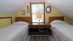 a bedroom with two beds and a table with a lamp at Cottage On Cambridge in Cape May Point